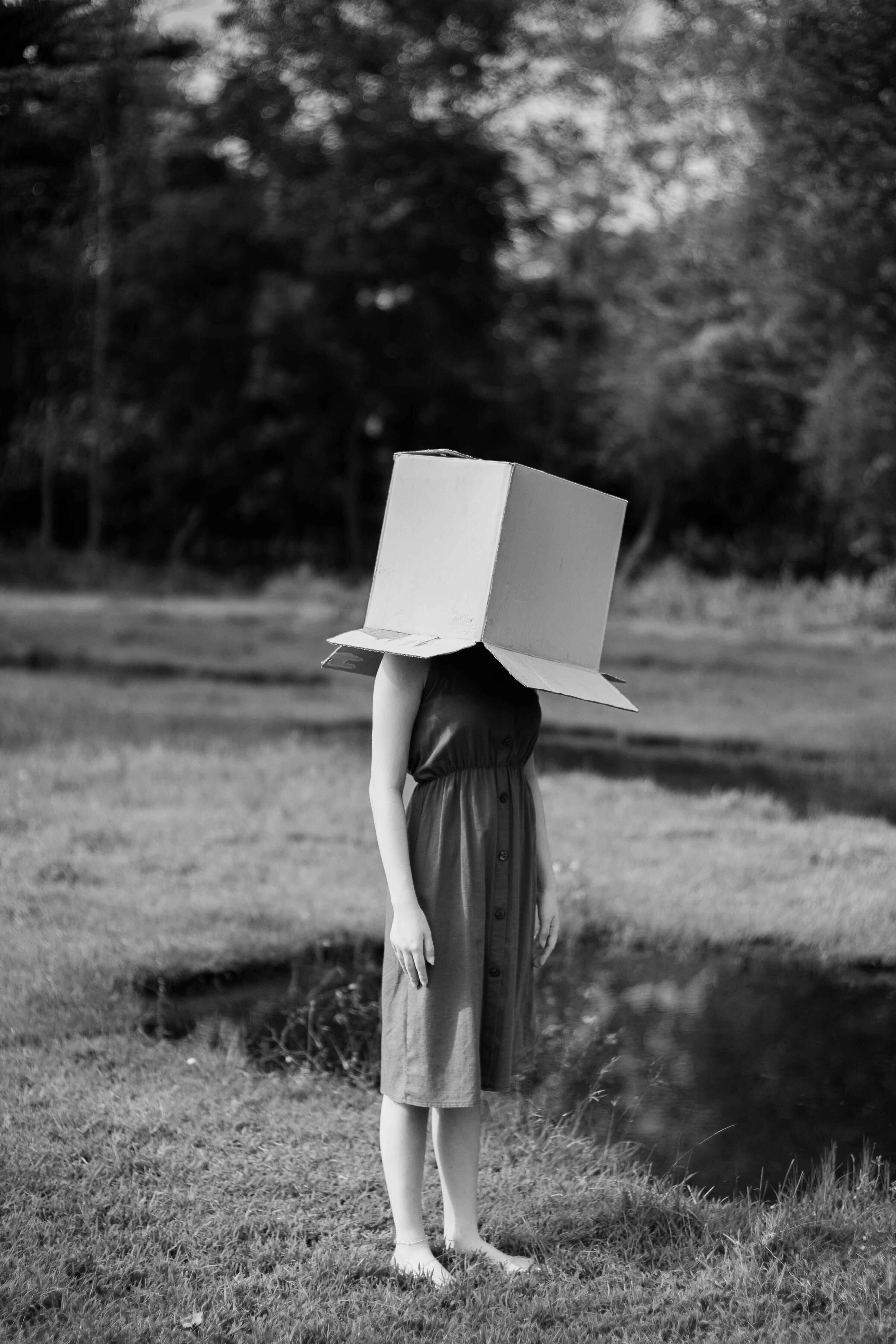 Person with cardboard box on their head standing in nature.